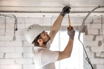 Electrician installer with a tool in his hands, working with cable on the construction site. Repair and handyman concept. House and house reconstruction.